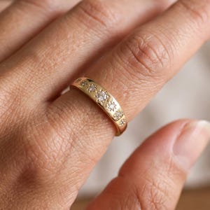 Close up hand wearing a seven stone celestial diamond ring with graduated star set lab grown diamonds on polished gold band