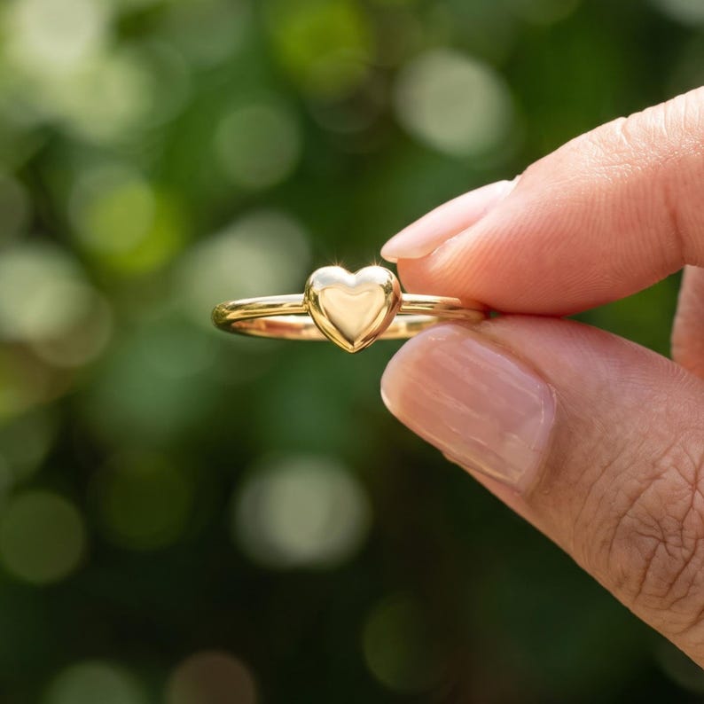 Back angle of minimalist heart ring showing the smooth circular shank and raised polished heart centerpiece.