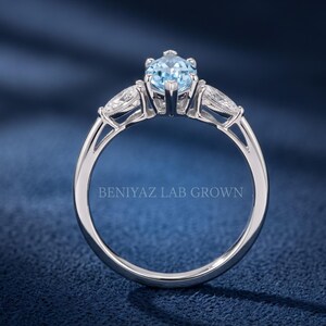 Side profile of a blue marquise lab grown diamond engagement ring showing the gallery, prong setting and pear side diamonds.