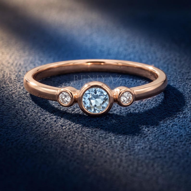 Close-up of a blue gemstone center stone framed by two round natural diamond accents in polished gold bezels.