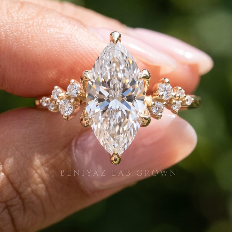 Close-up of marquise engagement ring with lab grown diamond center, vintage diamond cluster and detailed solid gold design.