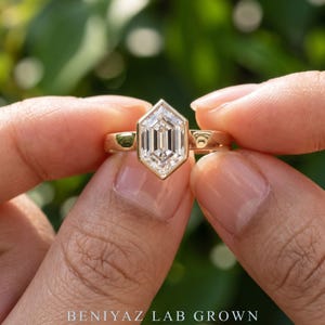 Hand-held outdoor view of a geometric hexagon lab grown diamond engagement ring showing the elongated step cut center stone and polished shank.