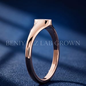Side profile of petite oval signet ring on blue background showing slim tapered shank and smooth polished construction