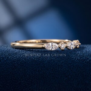 Close up marquise round diamond band held by hand, showing prong set mixed shape diamonds and slim 1.60 mm band