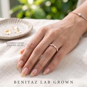 Woman wearing a delicate lab grown diamond wedding band with slim stacking design and mixed marquise round diamonds