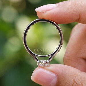 Rear view of a Dutch marquise solitaire engagement ring highlighting the polished double-line band, smooth rounded shank and elegant ring construction. Minimalist lab grown diamond jewelry photographed against a softly blurred green background.
