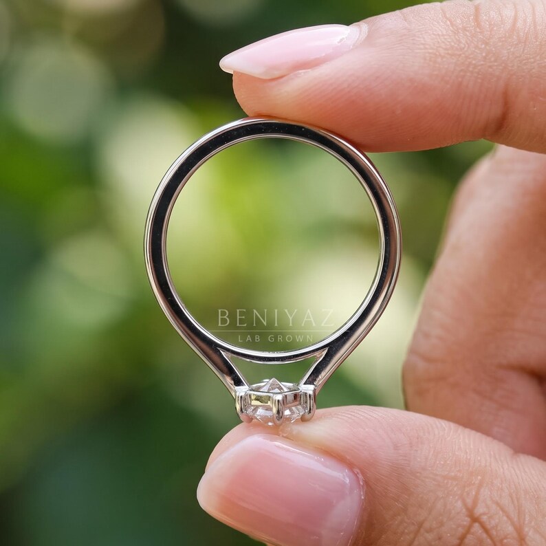 Rear view of a Dutch marquise solitaire engagement ring highlighting the polished double-line band, smooth rounded shank and elegant ring construction. Minimalist lab grown diamond jewelry photographed against a softly blurred green background.