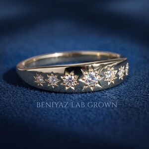 Seven stone celestial lab grown diamond band on blue background showing symmetrical star settings and high polish gold finish