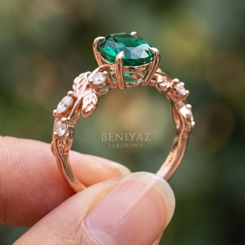 Close side view of leaf ring with oval lab created emerald, round accent stones and organic branch inspired setting.