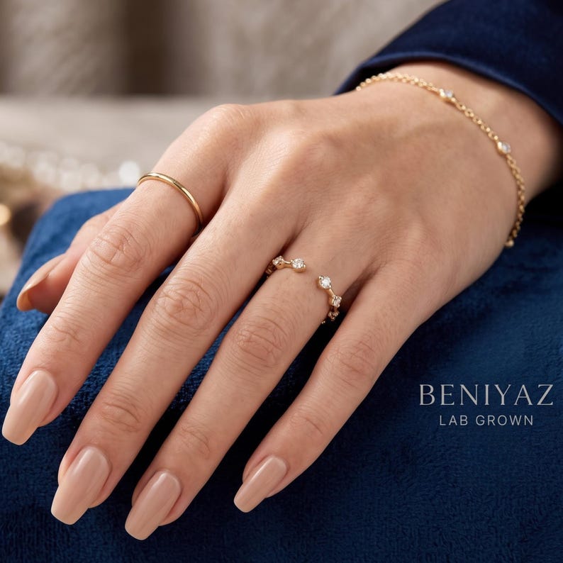May include: A gold open ring featuring small round clear stones, a thin gold band, and a delicate gold chain bracelet with embedded stones. The text BENIYAZ LAB GROWN is visible in the lower right corner of the image.