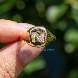 Yellow gold lab grown diamond initial signet ring worn on hand, personalized letter ring with modern luxury statement design