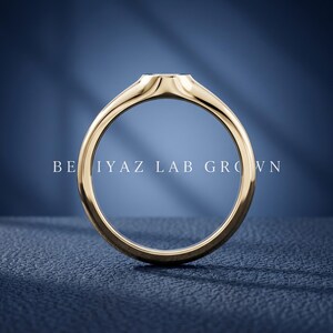 Rear view of petite oval signet ring on blue background showing tapered band, smooth interior and slim signet profile