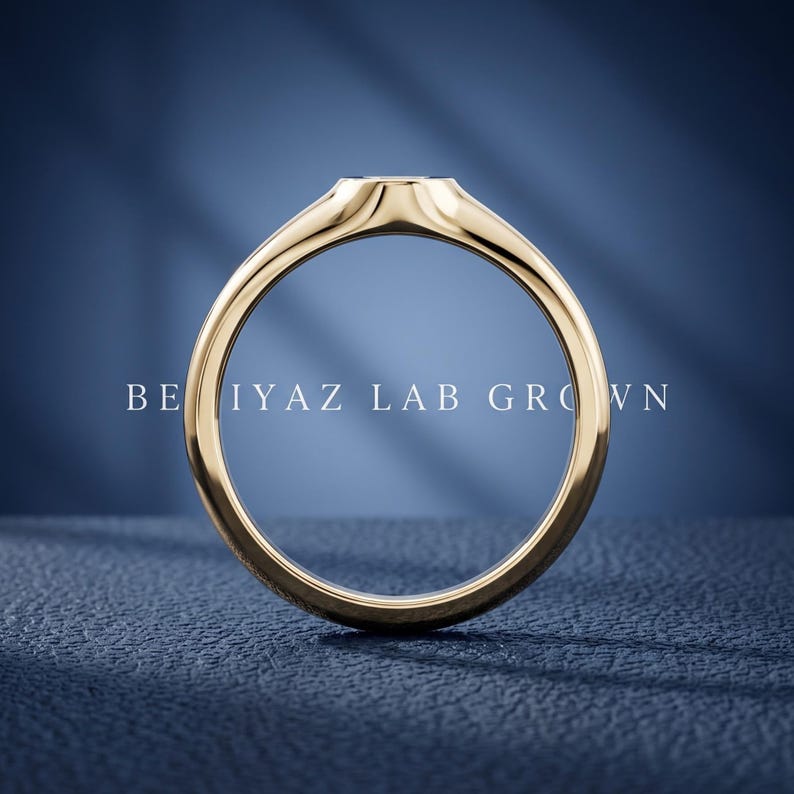 Rear view of petite oval signet ring on blue background showing tapered band, smooth interior and slim signet profile
