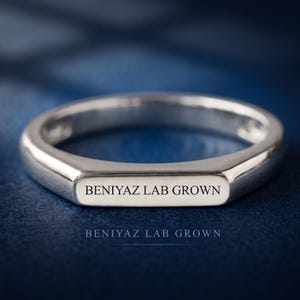 Hand-held side view of a custom bar signet ring showing the polished shank and low profile flat top design.