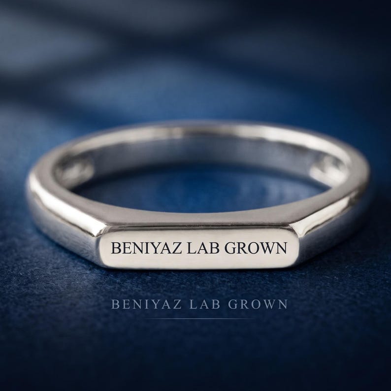 Hand-held side view of a custom bar signet ring showing the polished shank and low profile flat top design.