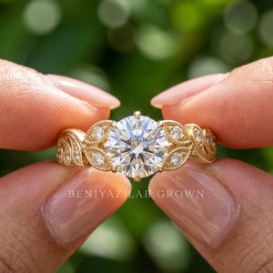 Close up hand view of a yellow gold round lab grown diamond ring featuring a brilliant center stone and side diamond accents against a natural green background