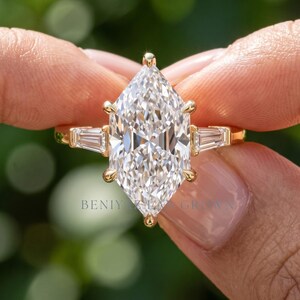 Close up elongated Dutch marquise engagement ring held by hand showing brilliant faceting and geometric side stone setting