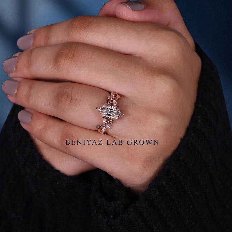 Rose gold marquise lab grown diamond engagement ring worn on hand, showing the elongated centre stone and intricate nature inspired band design.