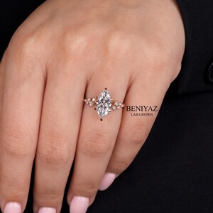 Vintage inspired marquise diamond ring worn on hand, featuring a lab grown diamond center and decorative cluster setting.