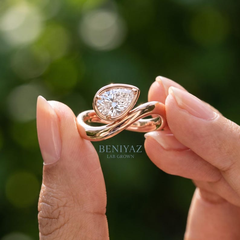 Close-up of the flowing infinity-inspired bypass shank that curves around the pear-shaped centre diamond.
