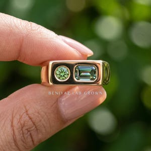 Close up hand photo of a teal sapphire signet ring with 0.71 CT emerald cut teal sapphire and 3.8mm round green sapphire side by side