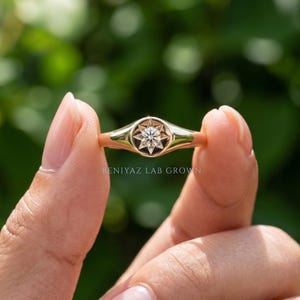 Diamond signet ring worn on hand featuring a champagne lab grown diamond in a small starburst celestial setting