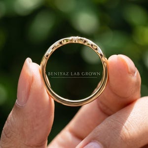 Close up of a yellow gold chevron contour wedding band on a blue background, showing the smooth 2mm curved profile.
