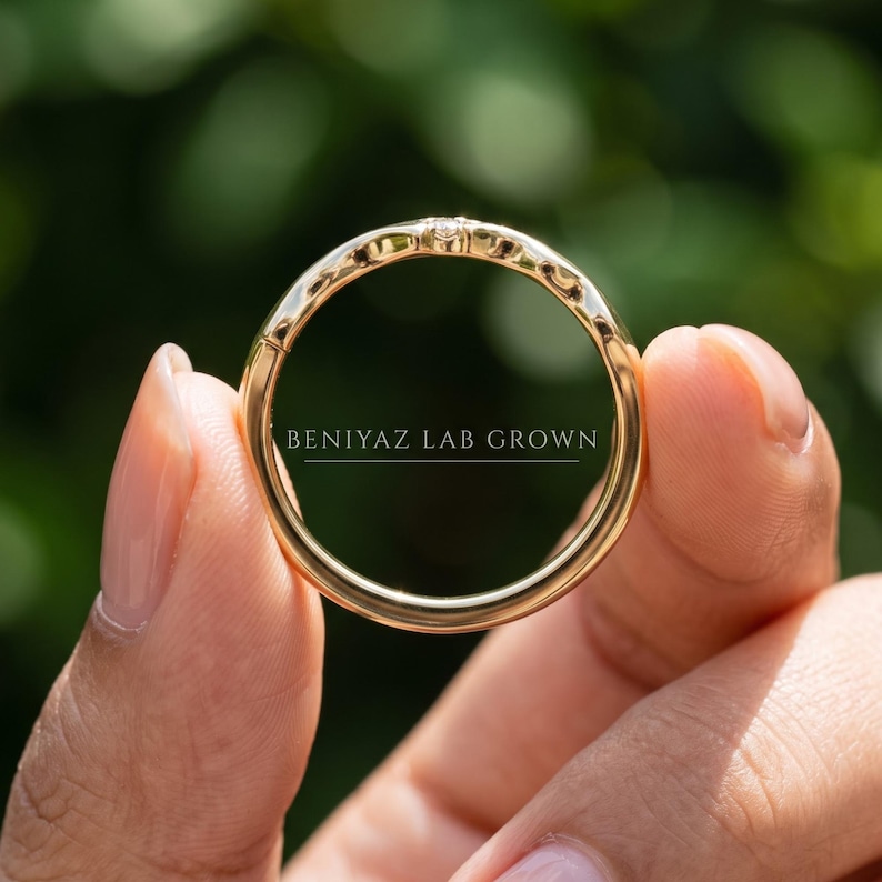 Close up of a yellow gold chevron contour wedding band on a blue background, showing the smooth 2mm curved profile.