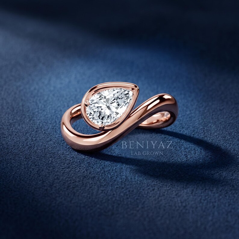 Three-quarter angle of a contemporary pear lab grown diamond ring with a polished flowing bypass design.