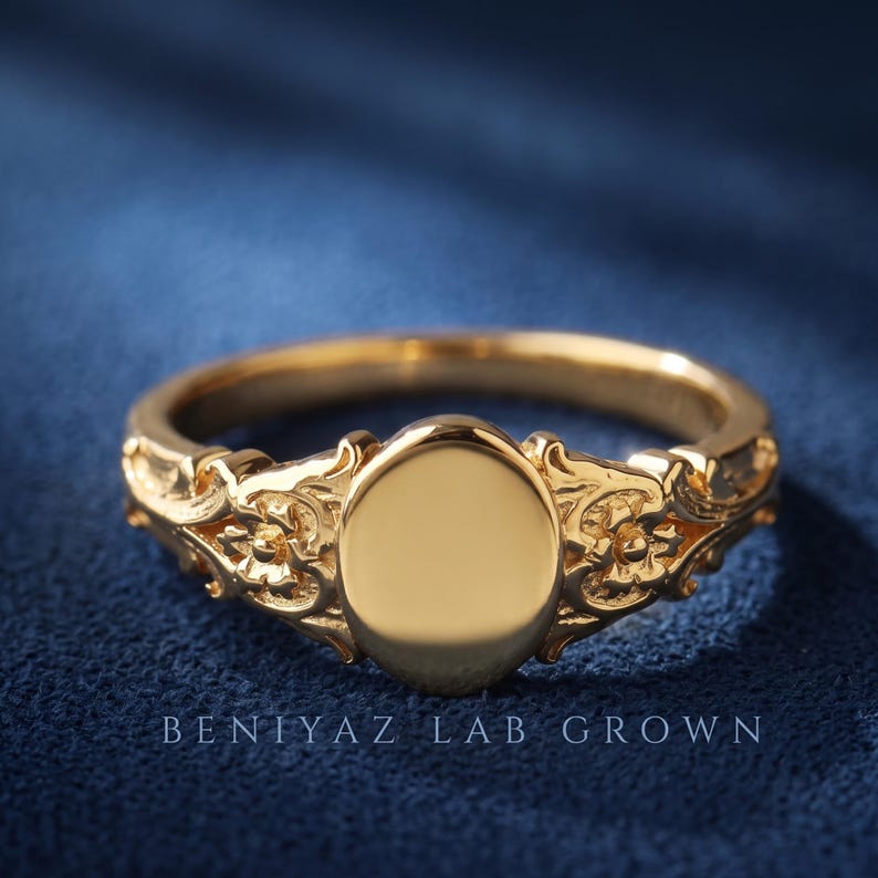 Blank oval signet ring in yellow gold showing the smooth 6 x 8 mm engraving face and detailed vintage floral shoulders.