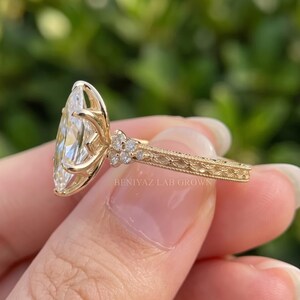 Low side angle of a marquise lab grown diamond engagement ring showing the pointed centre stone and detailed yellow gold setting.