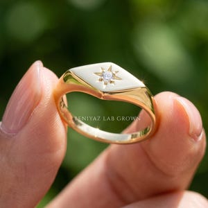Custom signet ring angled view showing elongated polished face, single diamond star setting and tapered gold band.