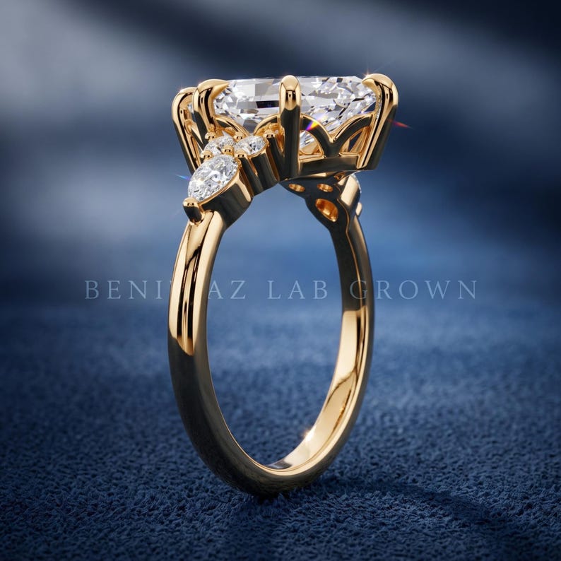 White metal marquise lab grown diamond engagement ring on blue velvet showing open gallery and side stone cluster setting