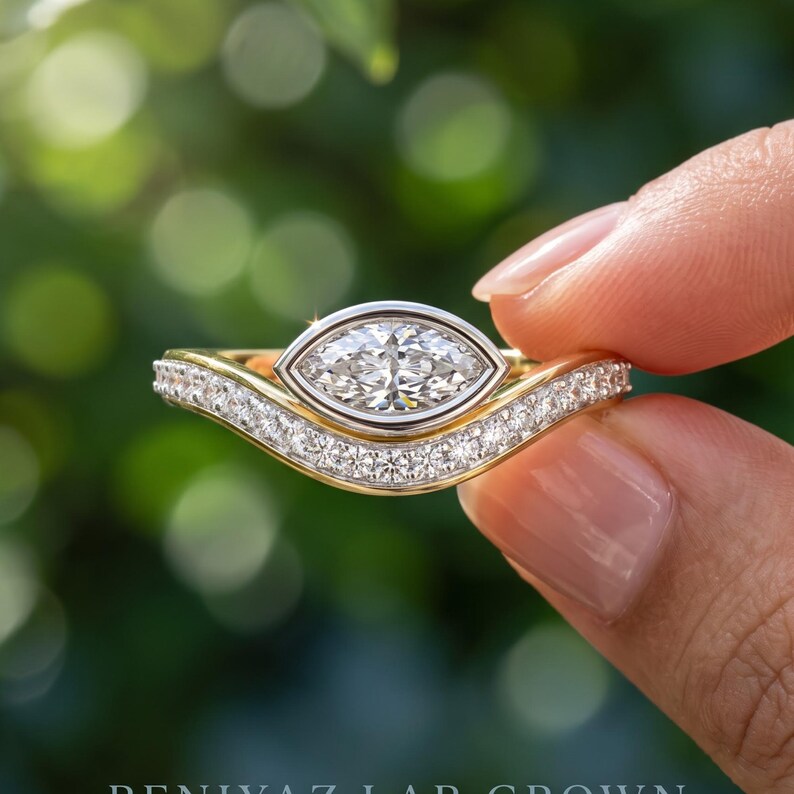 May include: A gold ring featuring a central marquise-cut stone set in a silver-toned bezel, with a curved band encrusted with small round pav&eacute;-set stones. The design follows a contoured shape, highlighting the contrast between the gold and silver.