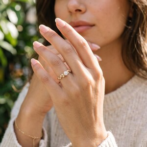 Lifestyle view of botanical lab grown diamond engagement ring worn on hand, a whimsical promise ring with round brilliant center.