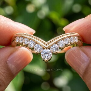 Close front view of moissanite chevron ring with larger center accent and graduated round stones across the V shaped band.