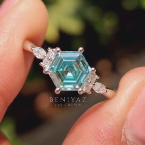 Anniversary gift ring with cyan blue moissanite center, geometric hexagon shape and elegant marquise accent stones.