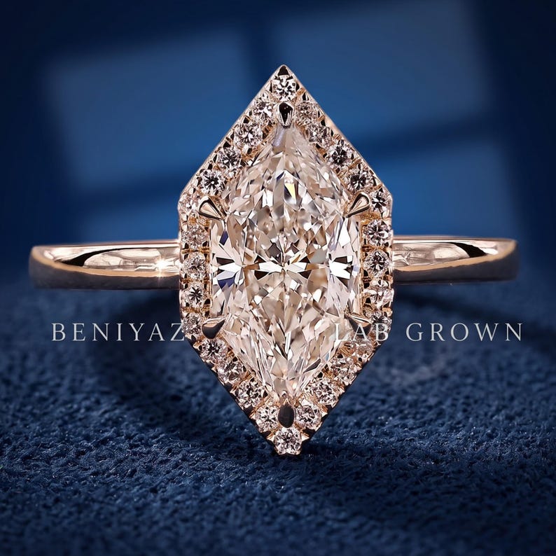 Rear hand held view of a Dutch marquise lab grown diamond halo engagement ring showing the slim polished gold shank and raised geometric setting.