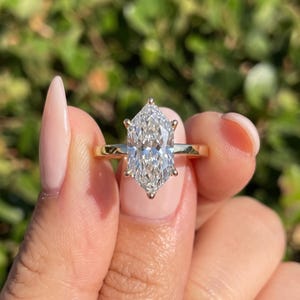 Plain band solitaire engagement ring with raised Dutch marquise lab grown diamond center stone and polished shank.