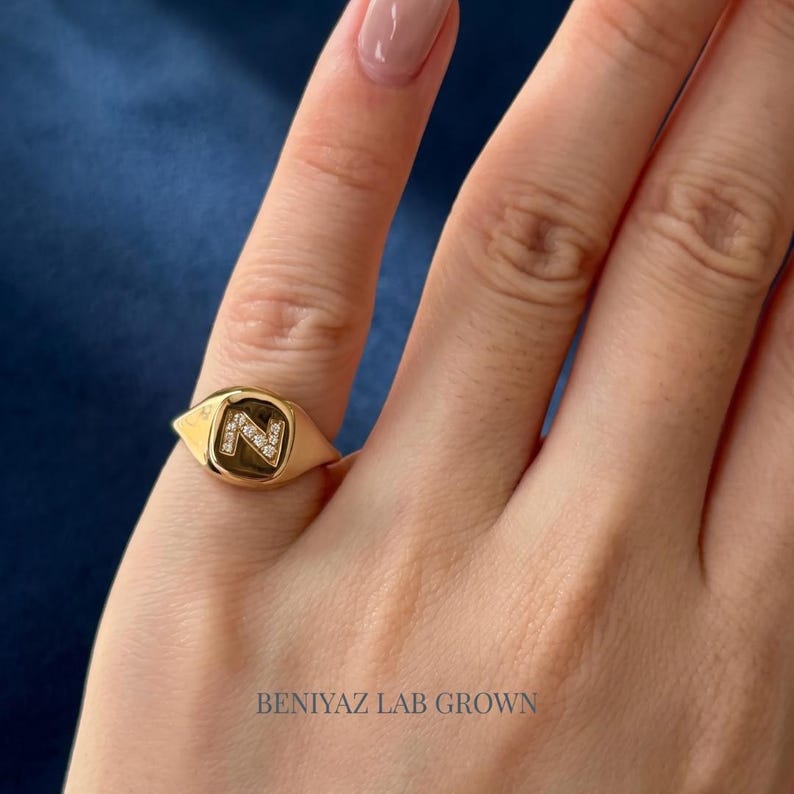 Solid gold personalized N signet ring photographed from the side, showing the smooth polished band, curved signet profile and lab grown diamond initial detail.