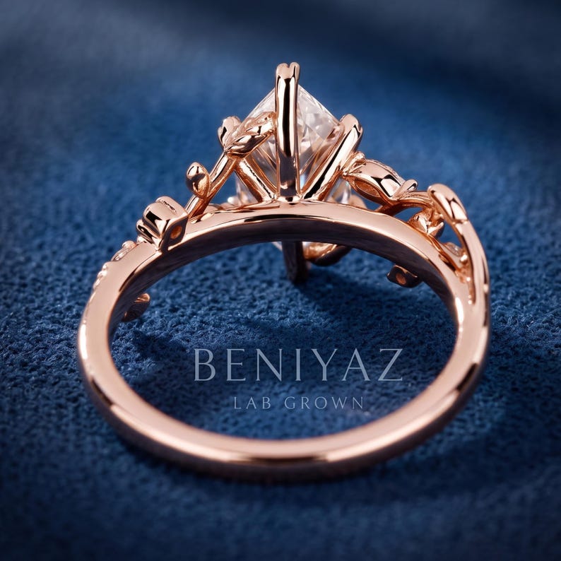 Back and angled view of a rose gold marquise diamond ring highlighting the decorative gallery, botanical shoulders and polished band.