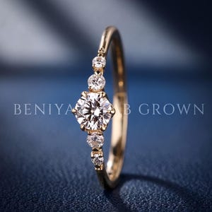 Detailed side view of a five stone lab grown diamond ring highlighting the raised centre diamond, graduated accents and open gallery design.