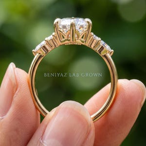 Side view of marquise engagement ring on blue velvet showing elevated center setting and decorative gallery structure