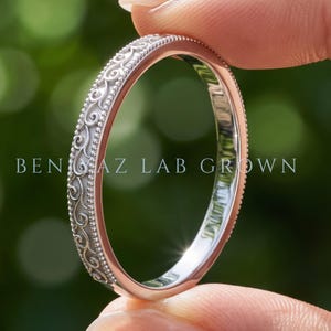 May include: A silver-toned metal ring featuring an intricate filigree scroll pattern along the outer band, bordered by delicate beaded edges. The text BEN GAZ LAB GROWN is visible across the center of the ring, which has a polished finish.