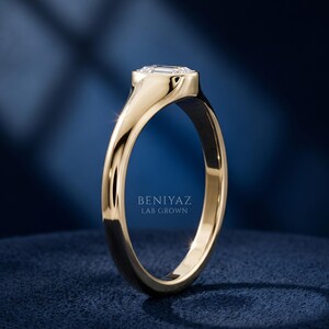 Side angle of petite oval signet ring on blue background showing raised oval face, tapered shoulders and polished band