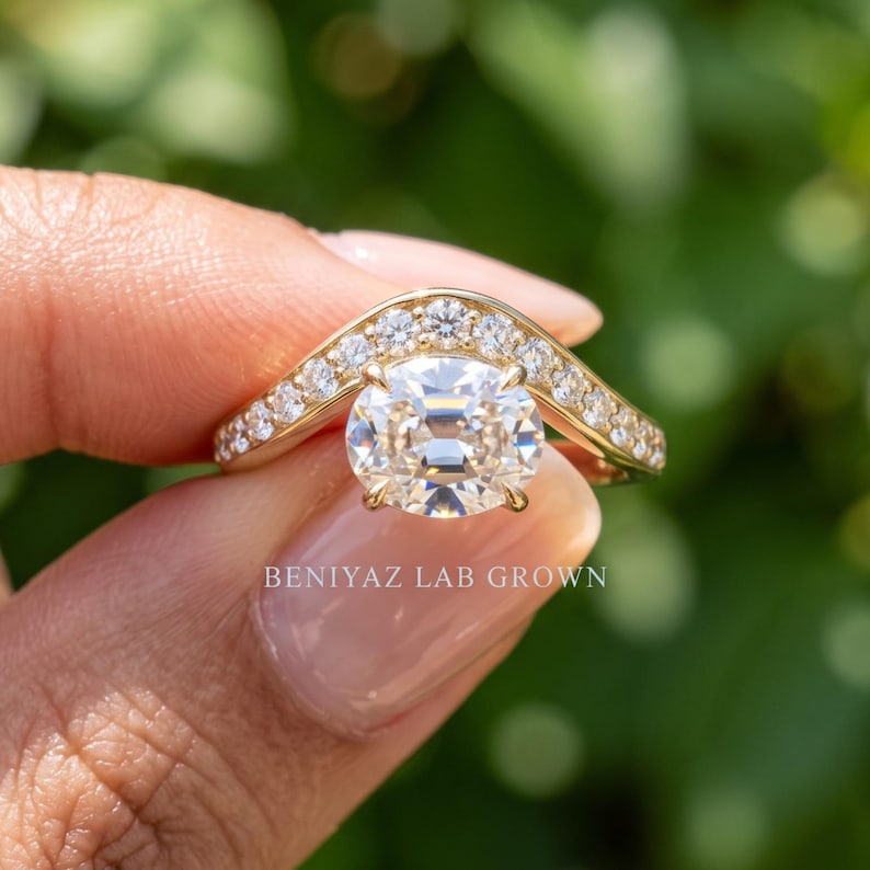 Detailed hand shot of a yellow gold antique style lab grown diamond engagement ring with a marquise inspired halo and pavé accents, photographed against a green background