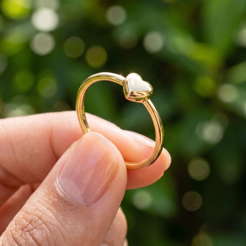 Side angle of puffy heart ring showing the raised polished heart and slim stackable band for women.