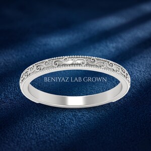 May include: A silver-toned metal ring featuring an intricate embossed scrollwork pattern along the outer band, bordered by delicate beaded edges. The text BENIYAZ LAB GROWN is printed in white lettering across the center of the ring band.