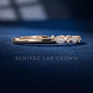 Angled view of lab grown diamond wedding band on blue background with alternating marquise and round stones