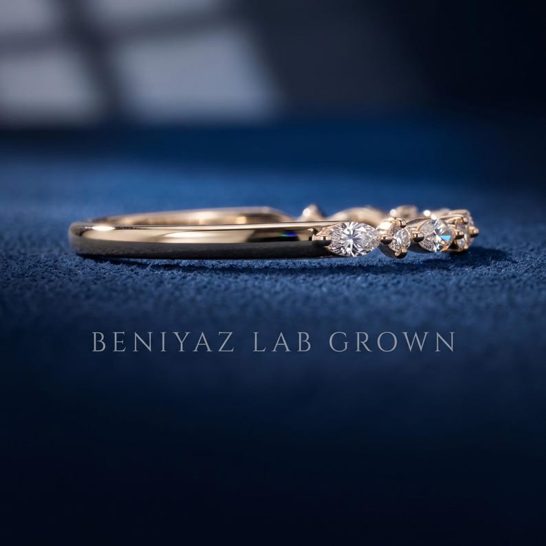 Angled view of lab grown diamond wedding band on blue background with alternating marquise and round stones